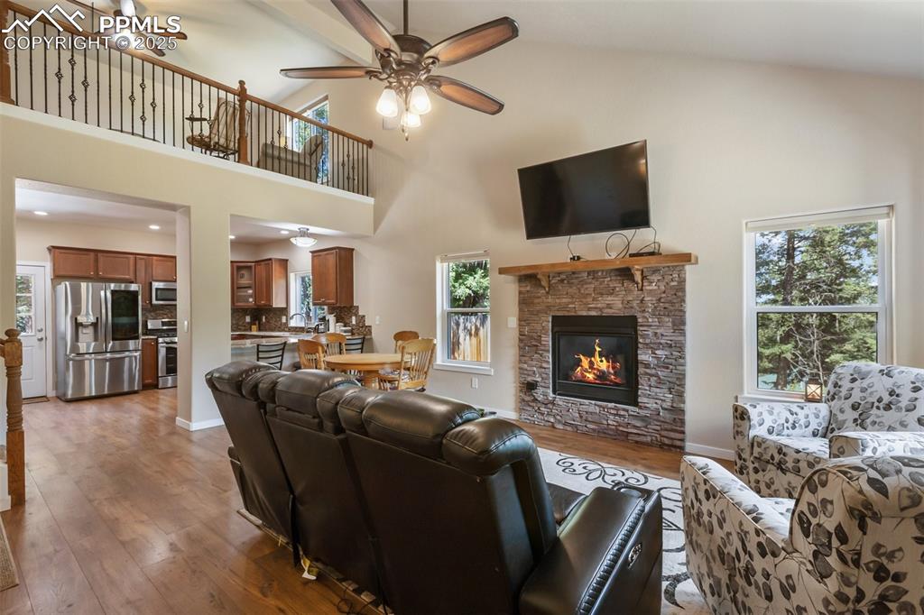 Image 16 of 46: Living area with a ceiling fan, wood finished floors, high vaulted ceiling,
