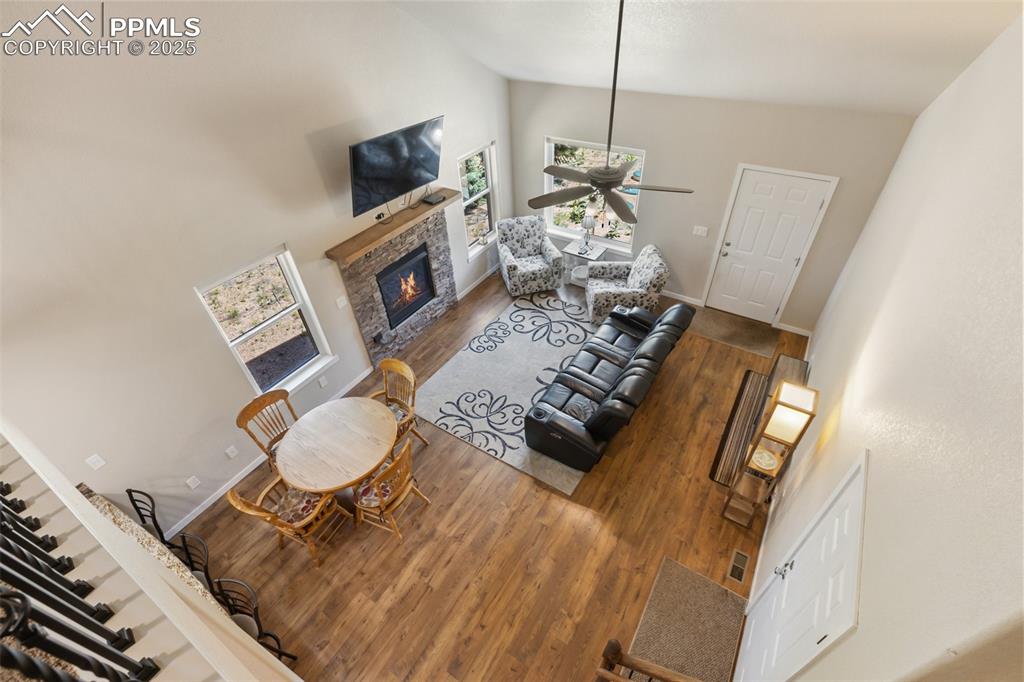 Image 17 of 46: Living area with high vaulted ceiling, a stone fireplace, ceiling fan, and