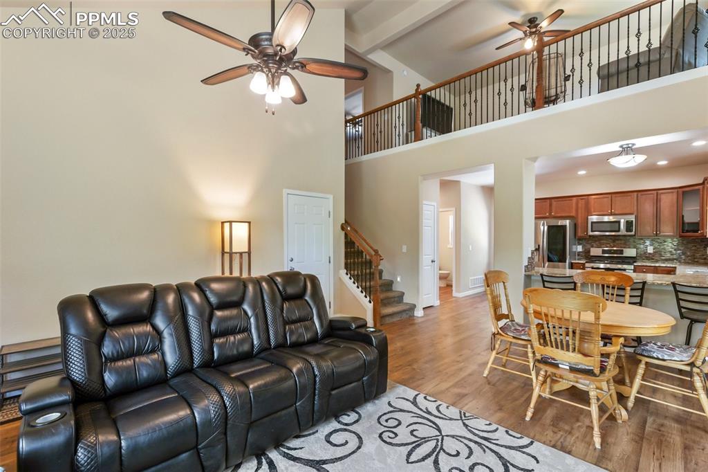 Image 18 of 46: Living area featuring a ceiling fan, light wood-style floors, stairway, hig
