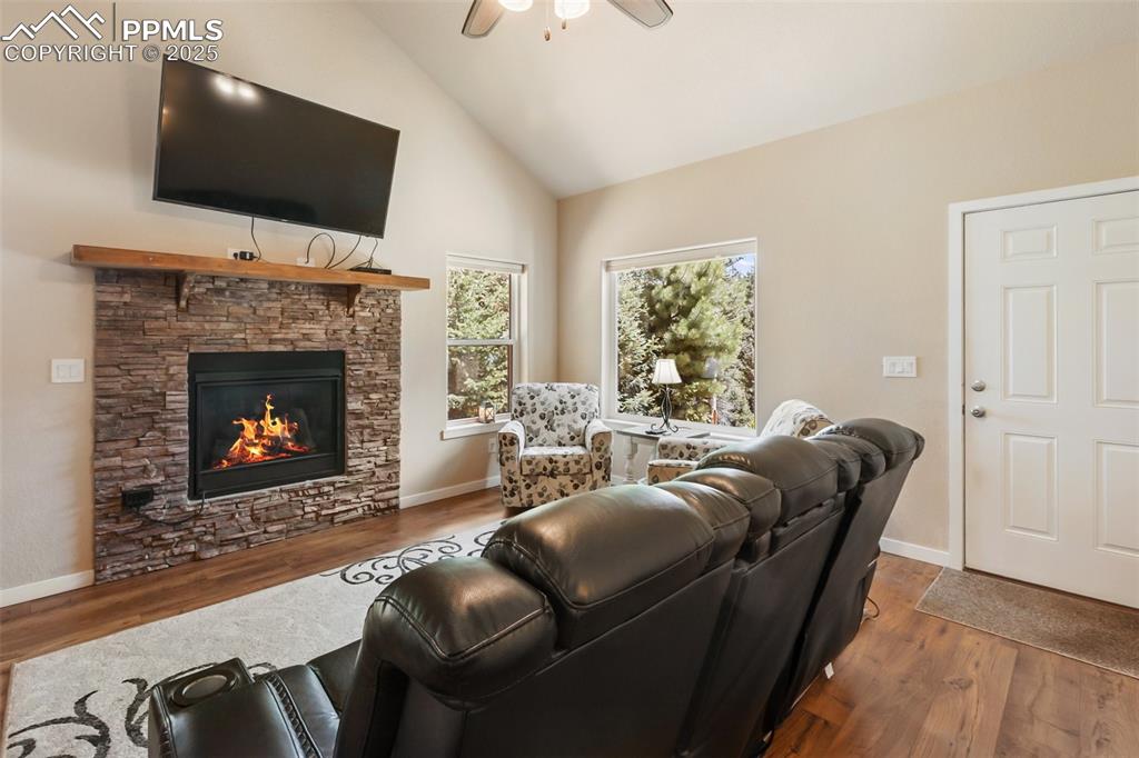 Image 19 of 46: Living room featuring a ceiling fan, wood finished floors, a stone fireplac