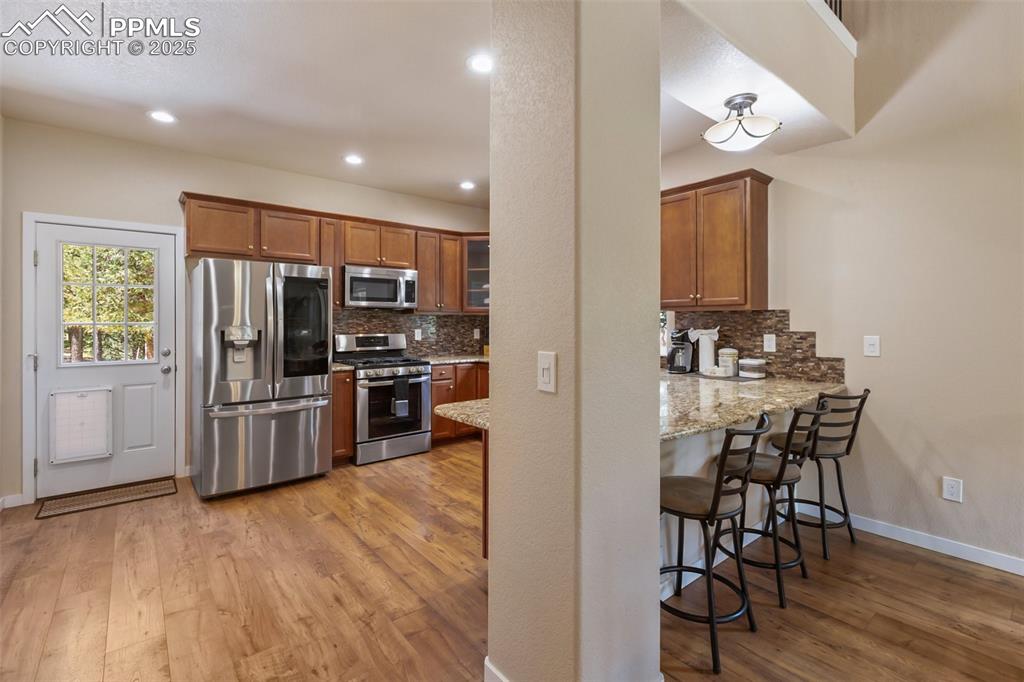 Image 22 of 46: Kitchen with appliances with stainless steel finishes, light wood-type floo