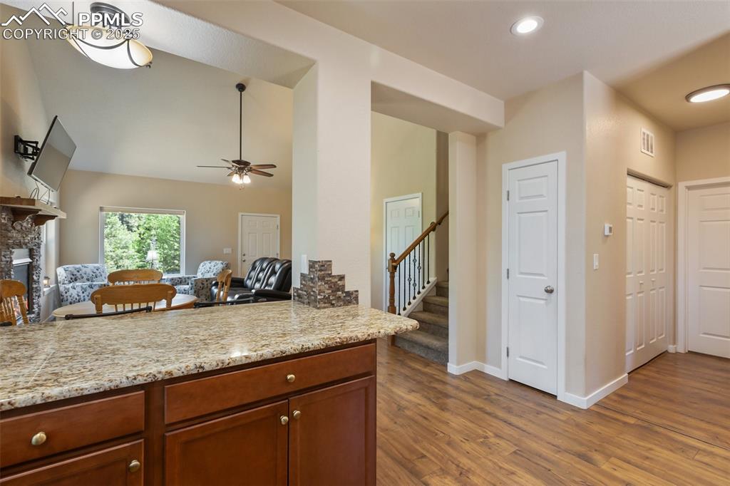 Image 26 of 46: Kitchen featuring dark wood-style floors, a ceiling fan, light stone counte