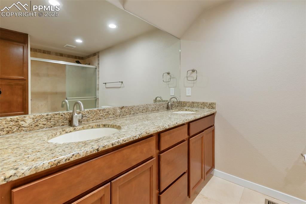 Image 33 of 46: Bathroom featuring double vanity, recessed lighting, a stall shower, and ti