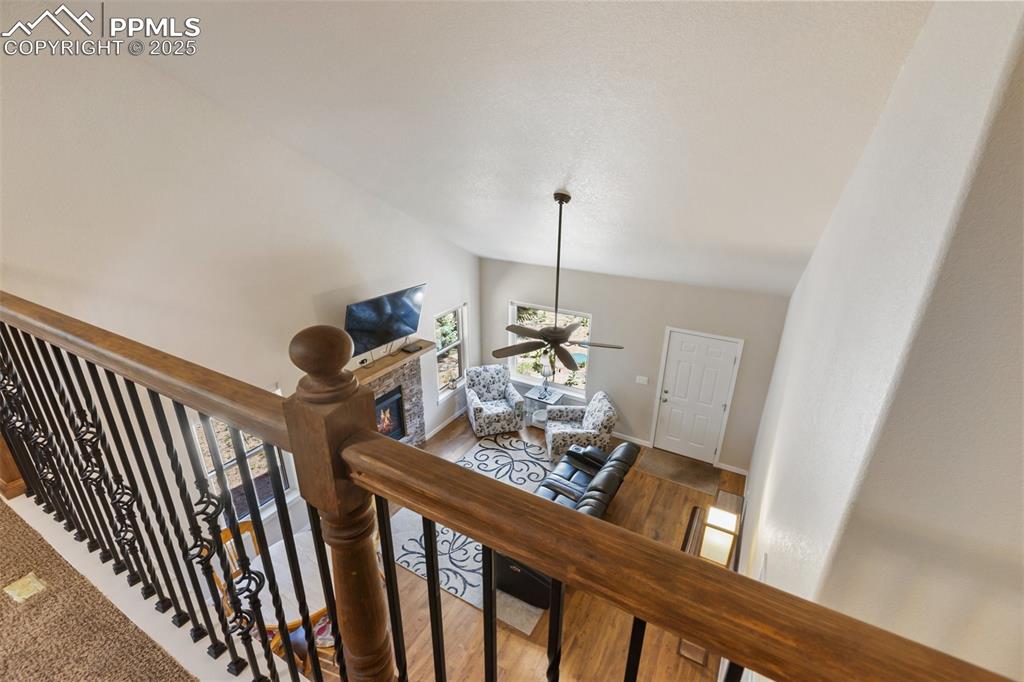 Image 39 of 46: Staircase with vaulted ceiling, ceiling fan, wood finished floors, and a fi