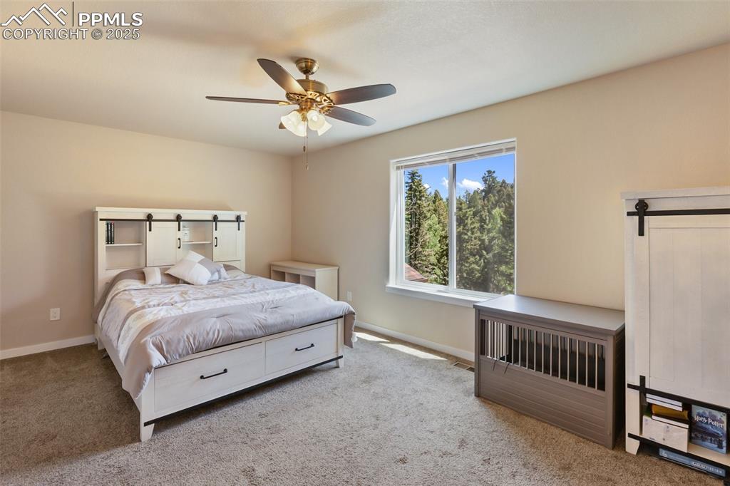 Image 41 of 46: Bedroom featuring carpet floors, a barn door, and ceiling fan