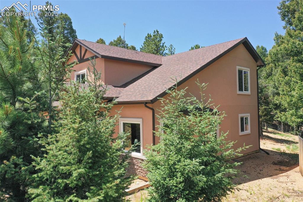 Image 7 of 46: View of side of home featuring stucco siding and a shingled roof