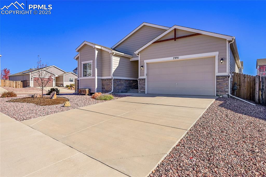 Image 30 of 43: View of front of house featuring stone siding, driveway, and an attached ga