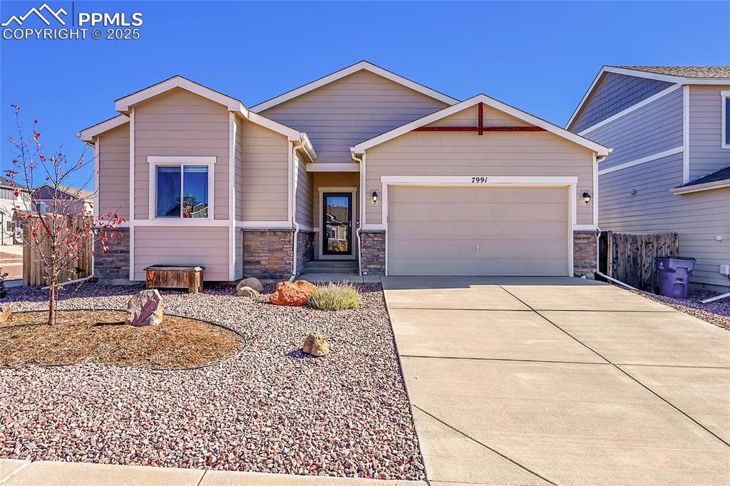Image 34 of 43: View of front of property with stone siding, concrete driveway, and an atta