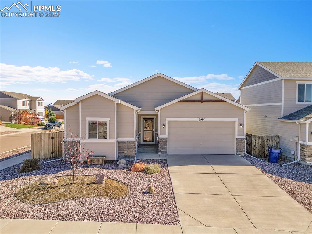 Image 35 of 43: View of front facade featuring a garage, stone siding, and concrete drivewa