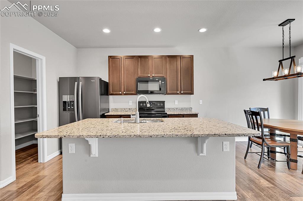 Image 7 of 43: Kitchen with light stone countertops, recessed lighting, a breakfast bar, a
