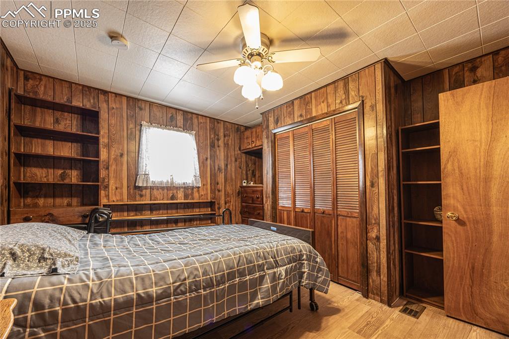 Image 18 of 34: Bedroom featuring wooden walls, wood finished floors, a closet, and a ceili