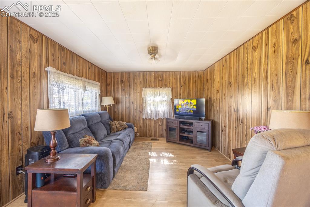 Image 4 of 34: Living room featuring wooden walls and light wood-style flooring