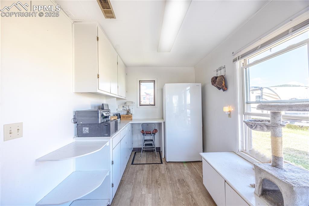 Image 9 of 34: Kitchen with freestanding refrigerator, white cabinetry, light wood-style f