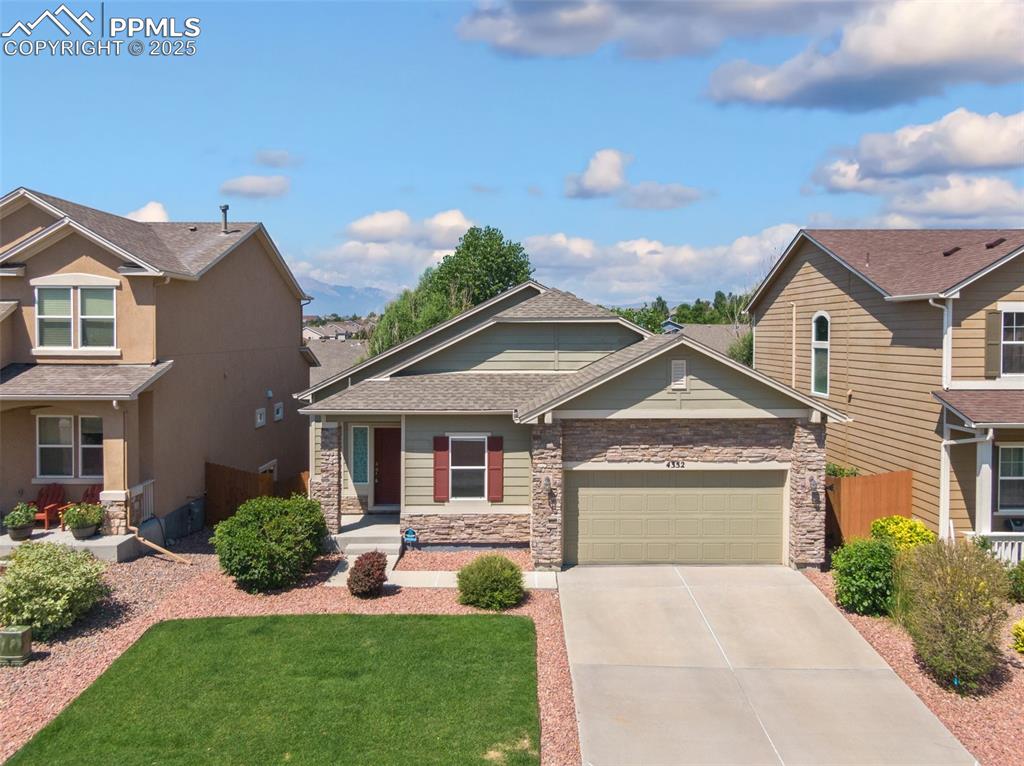 Caption: Craftsman-style home with a porch, concrete driveway, roof with shingles, stone siding, and an attac