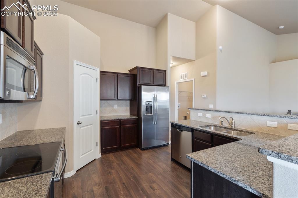 Image 10 of 45: Kitchen featuring backsplash, dark wood-type flooring, appliances with stai
