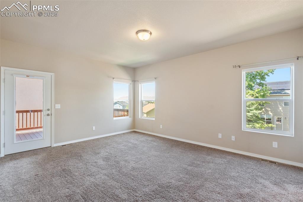 Image 13 of 45: Primary bedroom main level - Empty room with carpet flooring and baseboards