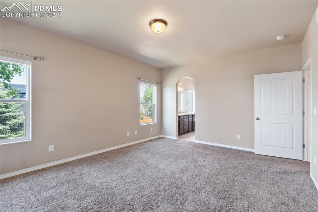 Image 14 of 45: Empty room with light colored carpet and arched walkways - Main Level