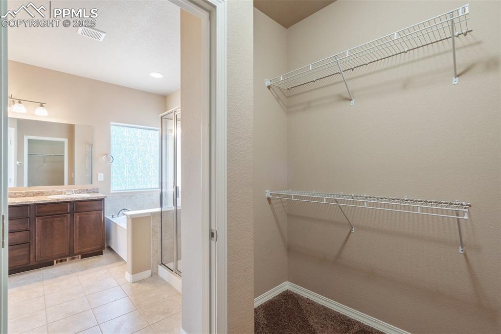 Image 16 of 45: Primary Bedroom Walk in closet with light tile patterned flooring and a sin
