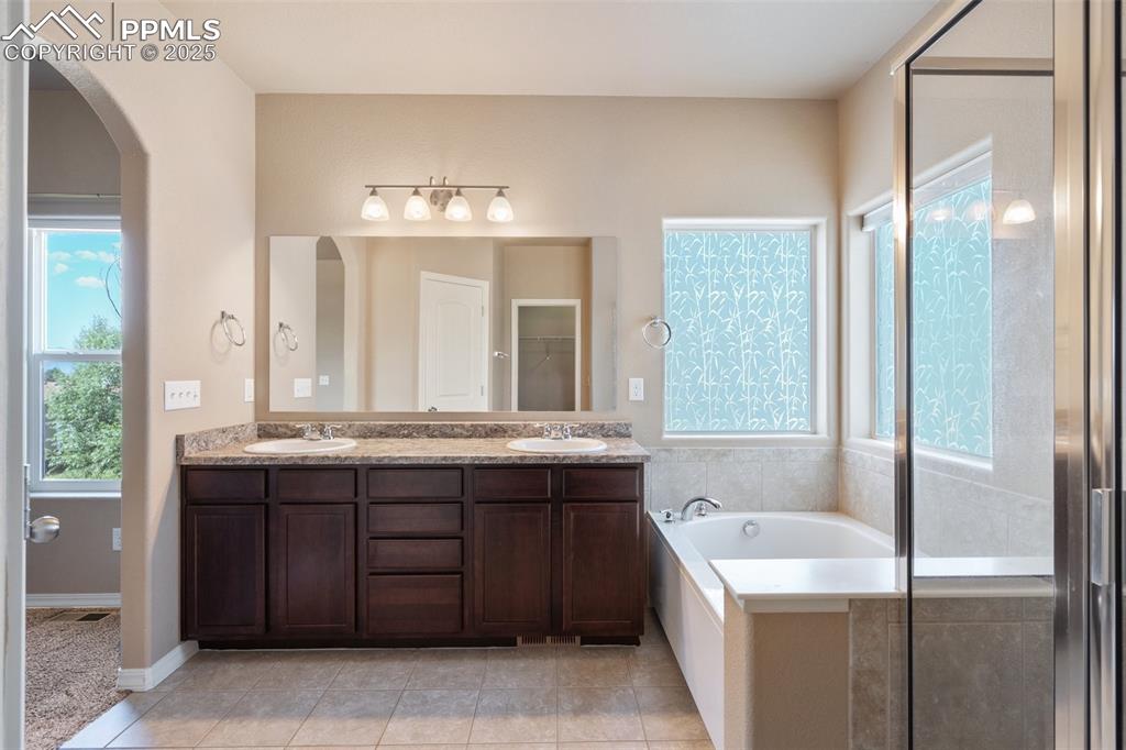 Image 17 of 45: Bathroom featuring double vanity, a garden tub, light tile patterned floors