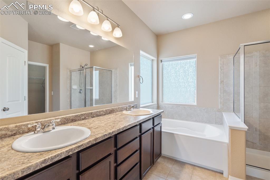 Image 19 of 45: Bathroom with a shower stall, a walk in closet, double vanity, a bath, and