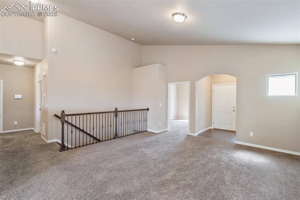 Image 6 of 45: Spare room with carpet flooring, arched walkways, and high vaulted ceiling