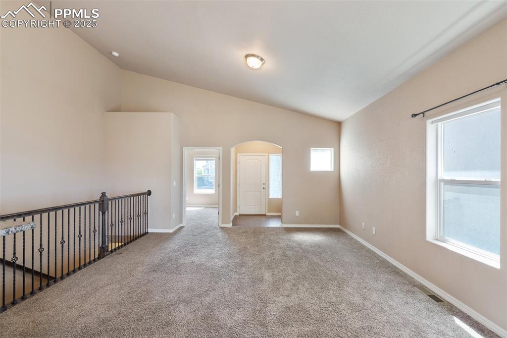 Image 8 of 45: Unfurnished room with arched walkways, carpet floors, and lofted ceiling
