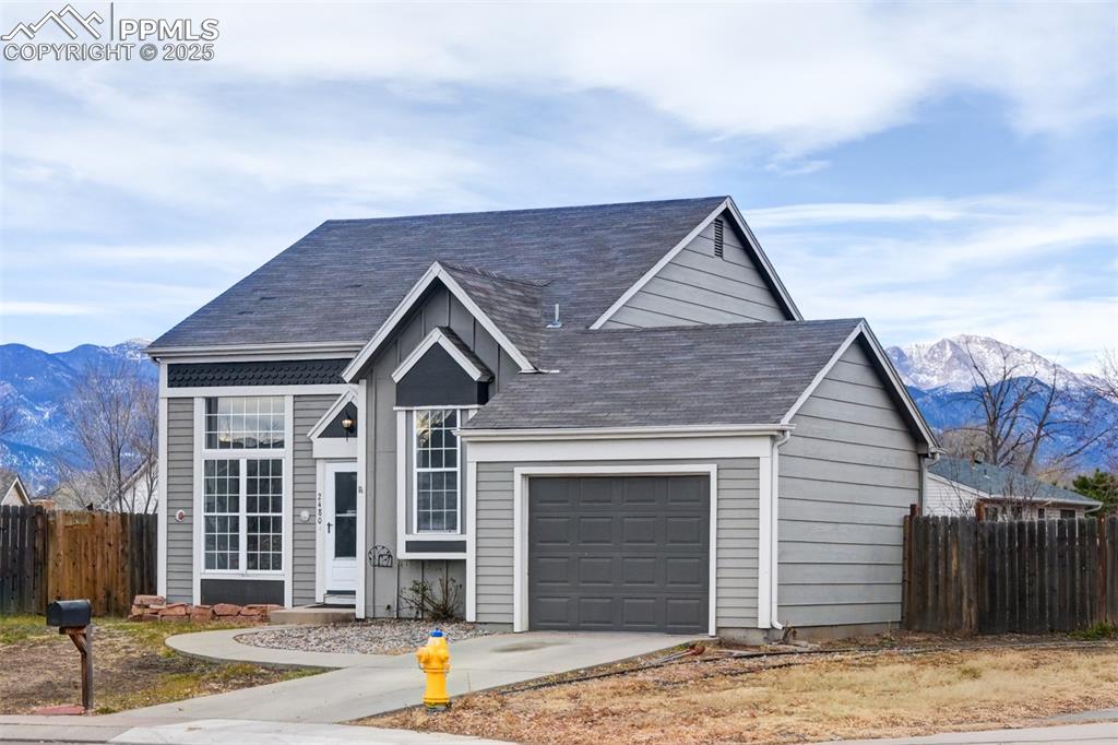Caption: View of front of property featuring a mountain view, a garage, concrete driveway, and roof with shin
