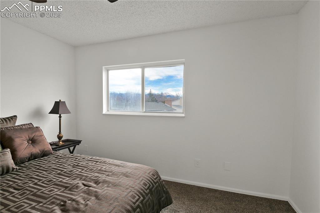 Image 13 of 28: Bedroom 1 on the upper level with a textured ceiling and ceiling fan