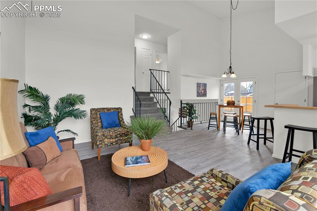 Image 3 of 28: Spacious Living area with a towering ceiling, a chandelier, wood finished f