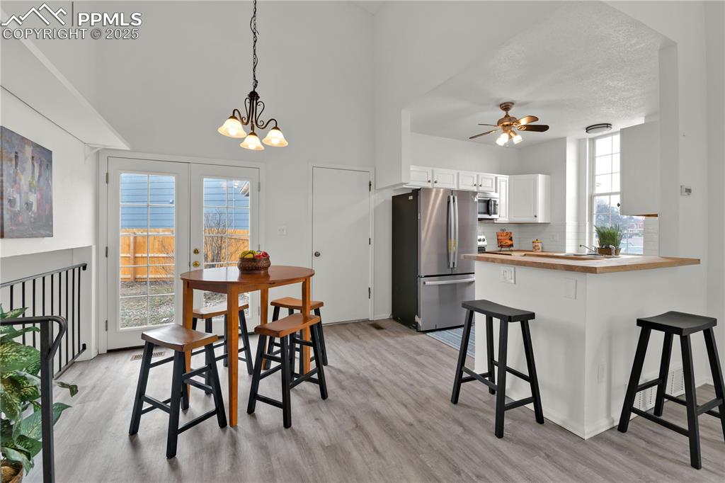 Image 5 of 28: Dining area with light wood-style flooring, a ceiling fan, a chandelier, an