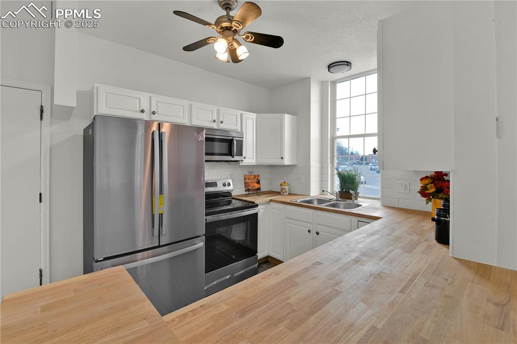 Image 8 of 28: Another view of the Kitchen with butcher block countertops, stainless steel