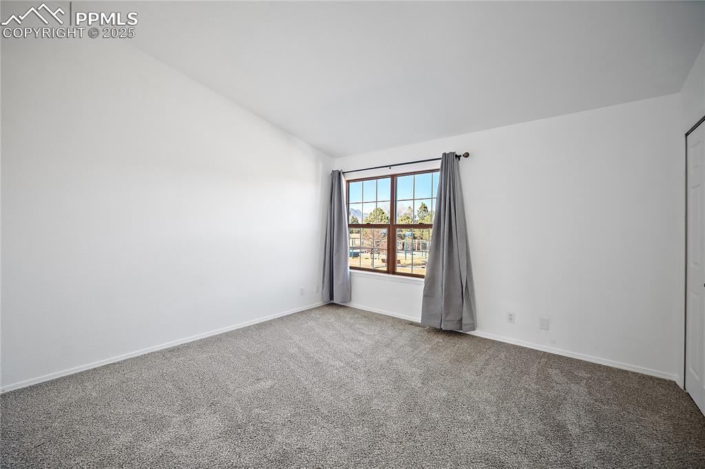 Image 21 of 42: Upstairs bedroom with vaulted ceilings. Large picture window over looks the
