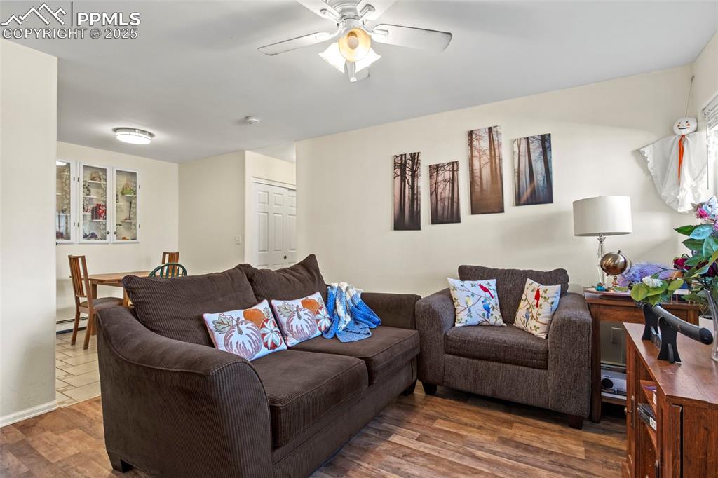 Image 5 of 21: Living area featuring wood finished floors, a ceiling fan, and a baseboard