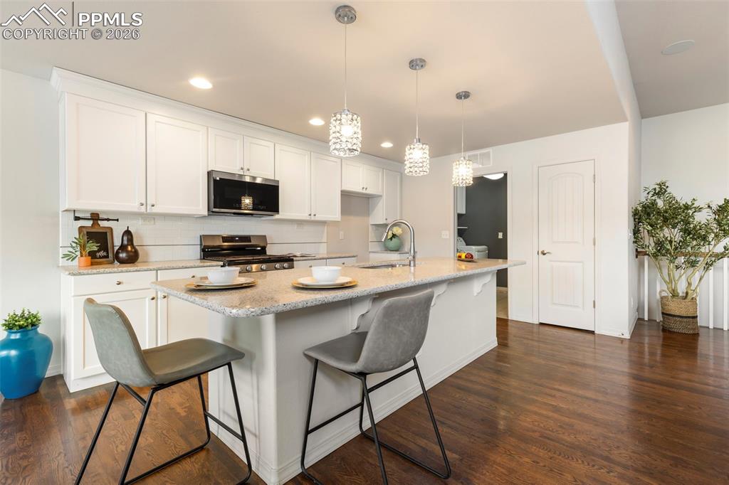 Image 8 of 44: Kitchen view highlighting gas range, stone countertops, and extended counte