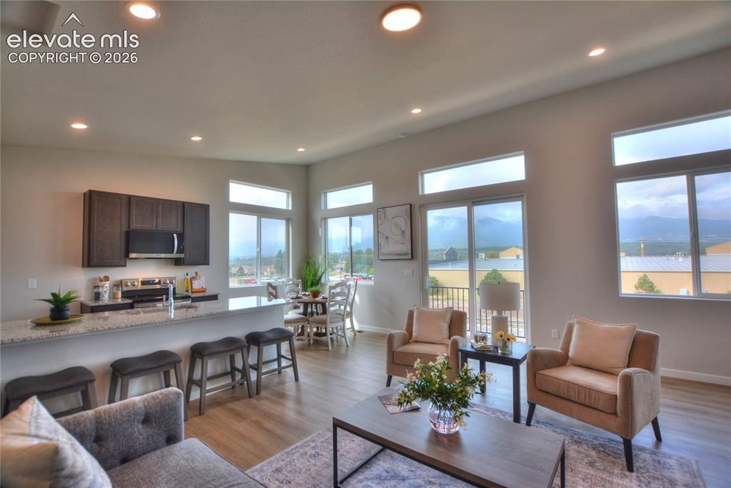 Image 13 of 25: Open-concept living space with wood-finish flooring, recessed lighting, and