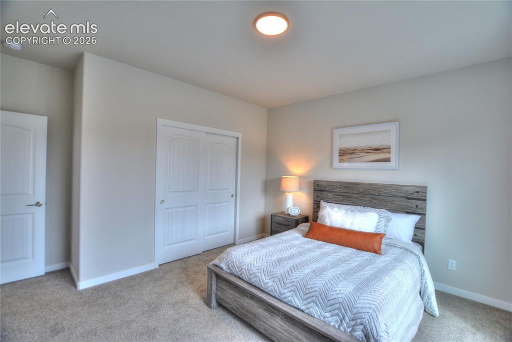 Image 18 of 25: Spacious bedroom featuring a wood-finish platform bed, dual nightstands wit