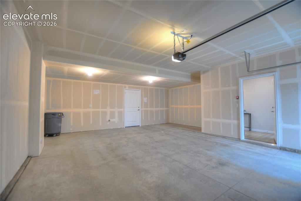 Image 22 of 25: Concrete flooring with two interior doors, overhead lighting, and an automa