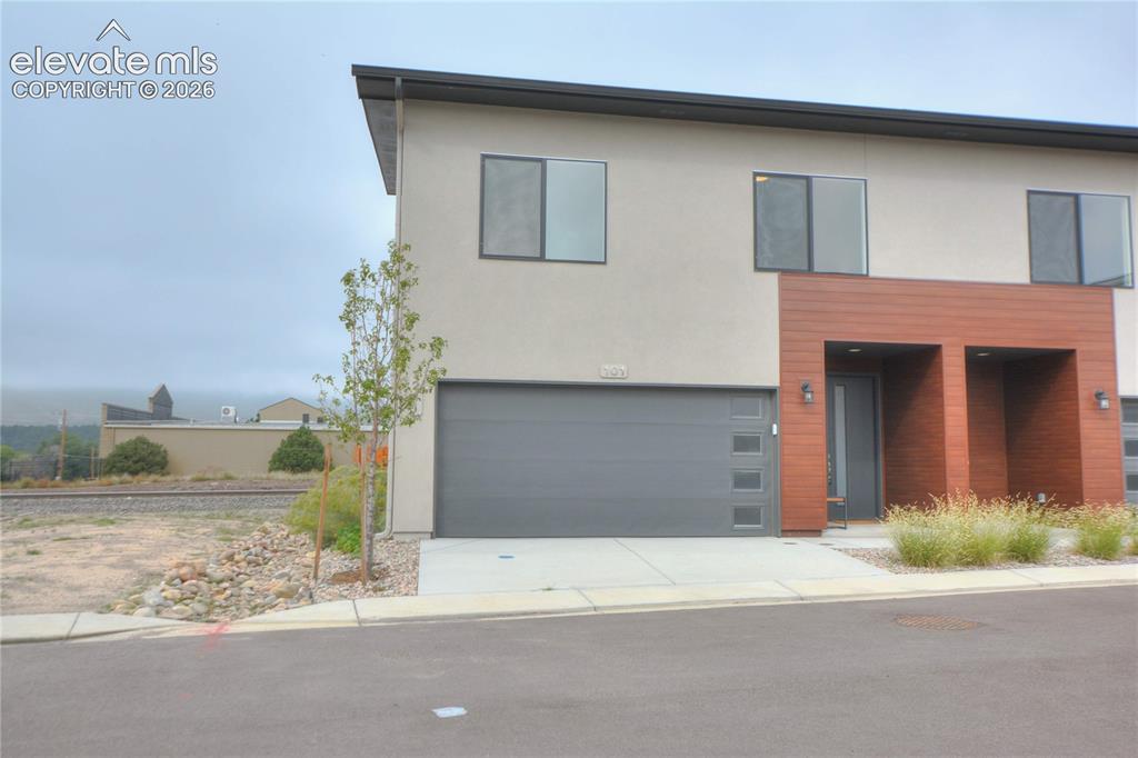 Image 3 of 25: Contemporary exterior design featuring stucco and wood-finish siding, an at
