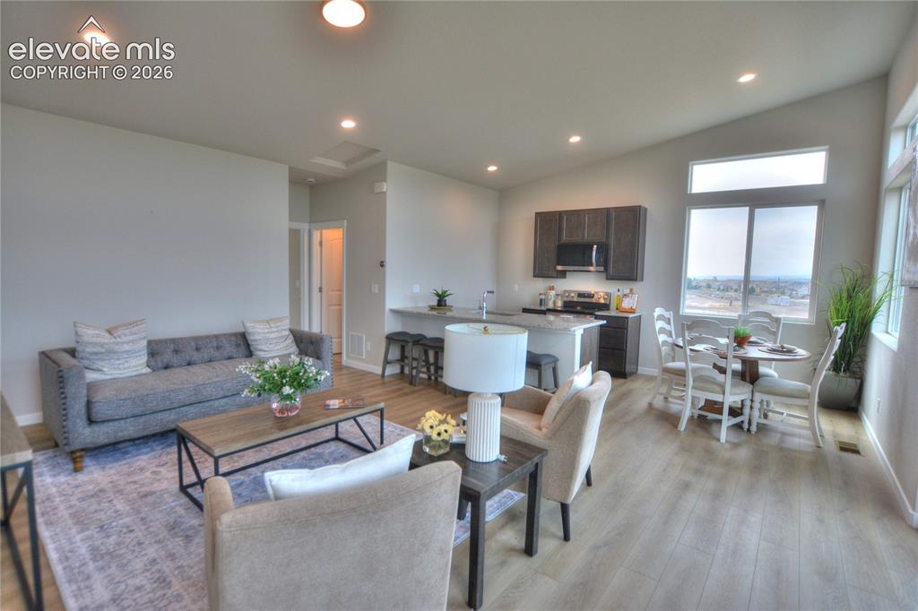 Image 7 of 25: Open-concept living area with wood-finish flooring, recessed lighting, and