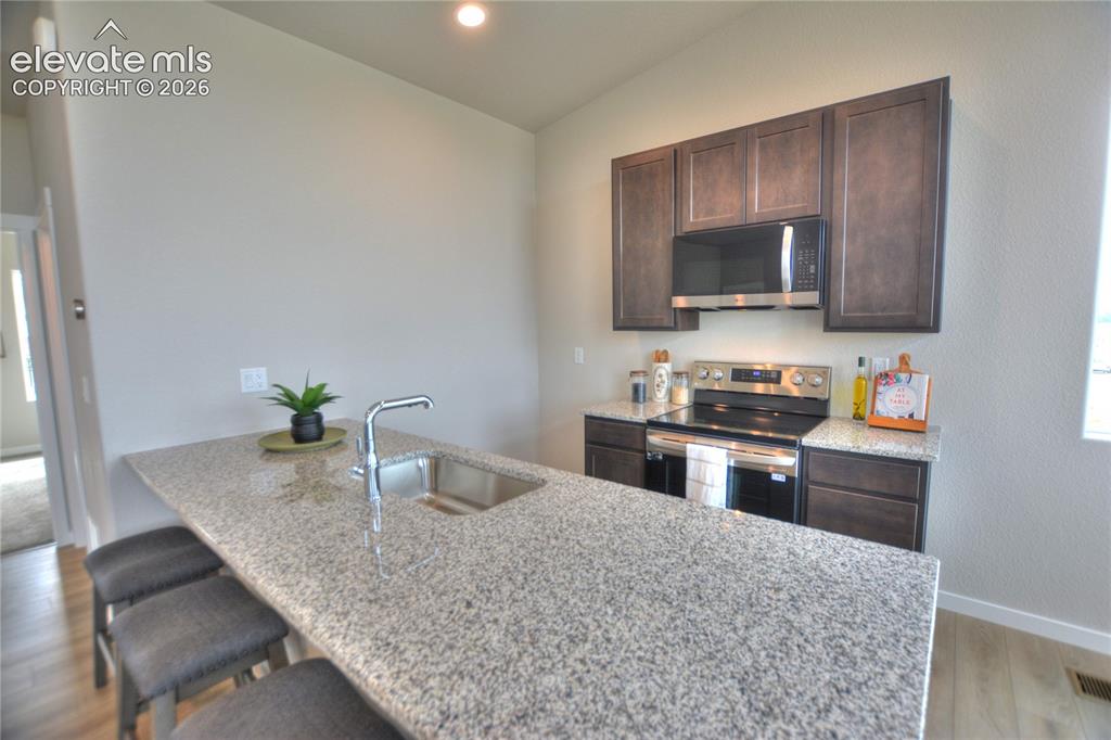 Image 8 of 25: Granite-style countertop with an undermount sink, stainless steel faucet, d