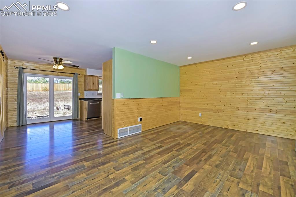 Image 10 of 39: Unfurnished room featuring wood walls, dark wood finished floors, recessed