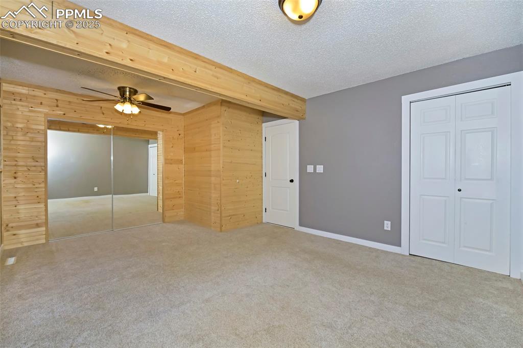 Image 18 of 39: Unfurnished bedroom featuring wood walls, carpet floors, a textured ceiling