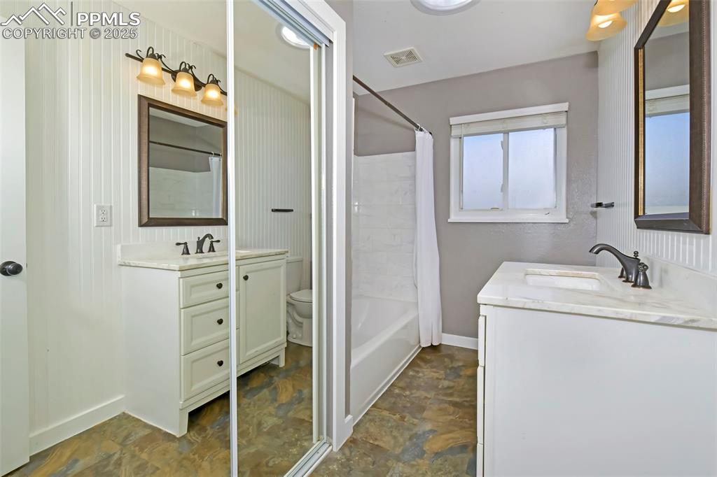 Image 20 of 39: Full bath with vanity, stone finish floors, and shower / bath combination w