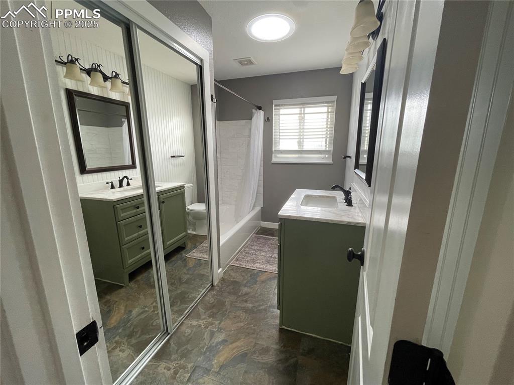 Image 21 of 39: Bathroom featuring shower / bath combo with shower curtain and two vanities