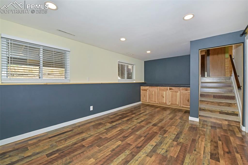 Image 24 of 39: Unfurnished room with recessed lighting, dark wood-style floors, and stairs