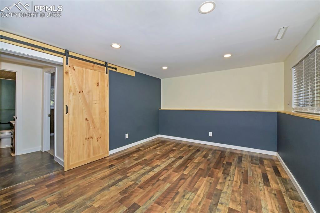 Image 25 of 39: Spare room with wood finished floors, recessed lighting, and a barn door