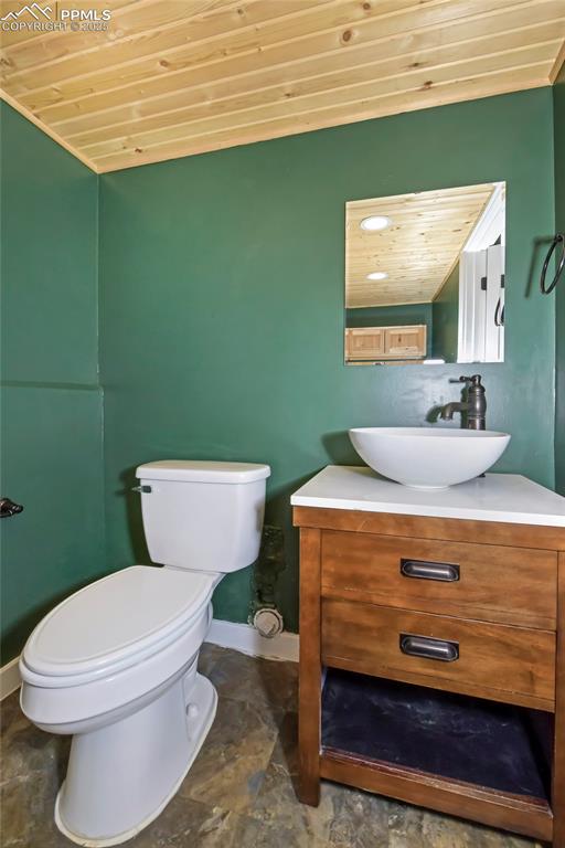 Image 28 of 39: Bathroom with wooden ceiling, vanity, and stone finish flooring