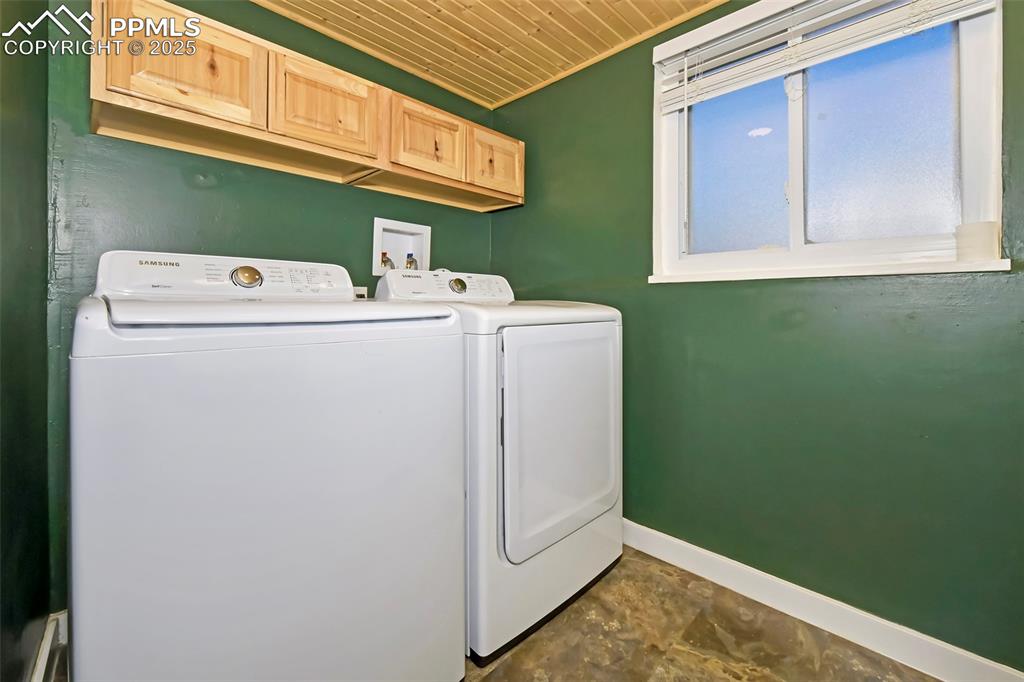 Image 29 of 39: Washroom with wood ceiling, washing machine and dryer, and dark stone finis