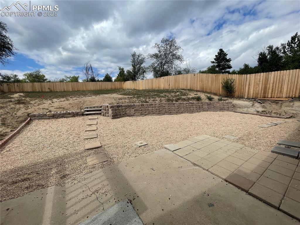 Image 33 of 39: Fenced backyard with a patio