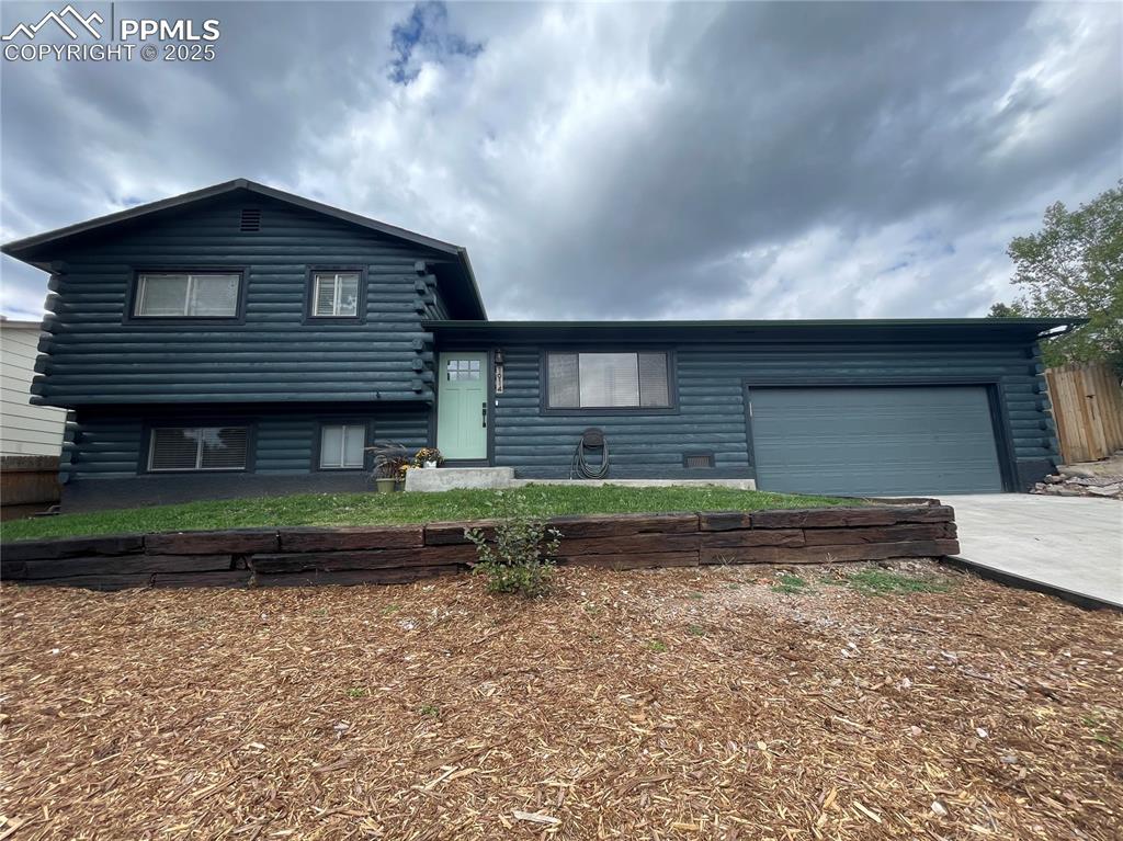 Image 4 of 39: View of front of home with log exterior, concrete driveway, and an attached